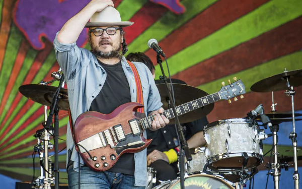 HD desktop wallpaper featuring a musician on stage with a guitar, set against a vibrant, artistic backdrop.