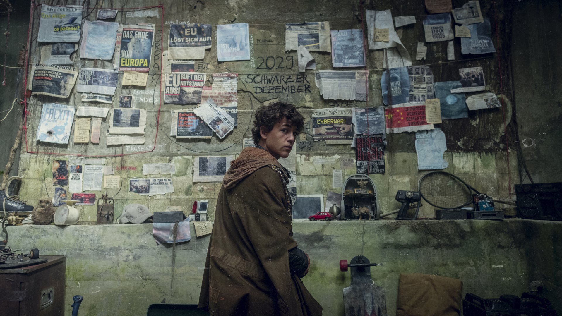 HD desktop wallpaper from Tribes of Europa featuring a character in a room plastered with posters and notes.