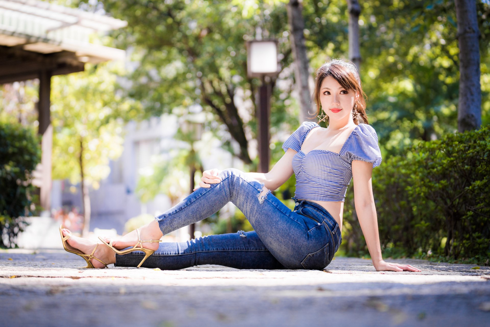 An Asian brunette model in high heels poses on a sunlit path with a soft depth of field, captured in 4K Ultra HD for a vibrant desktop wallpaper.