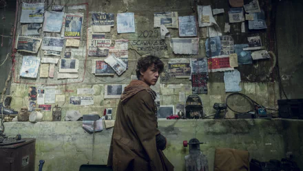 HD desktop wallpaper from Tribes of Europa featuring a character in a room plastered with posters and notes.