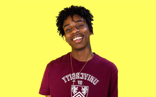 HD desktop wallpaper of a smiling person sporting a maroon top with a bright yellow background.