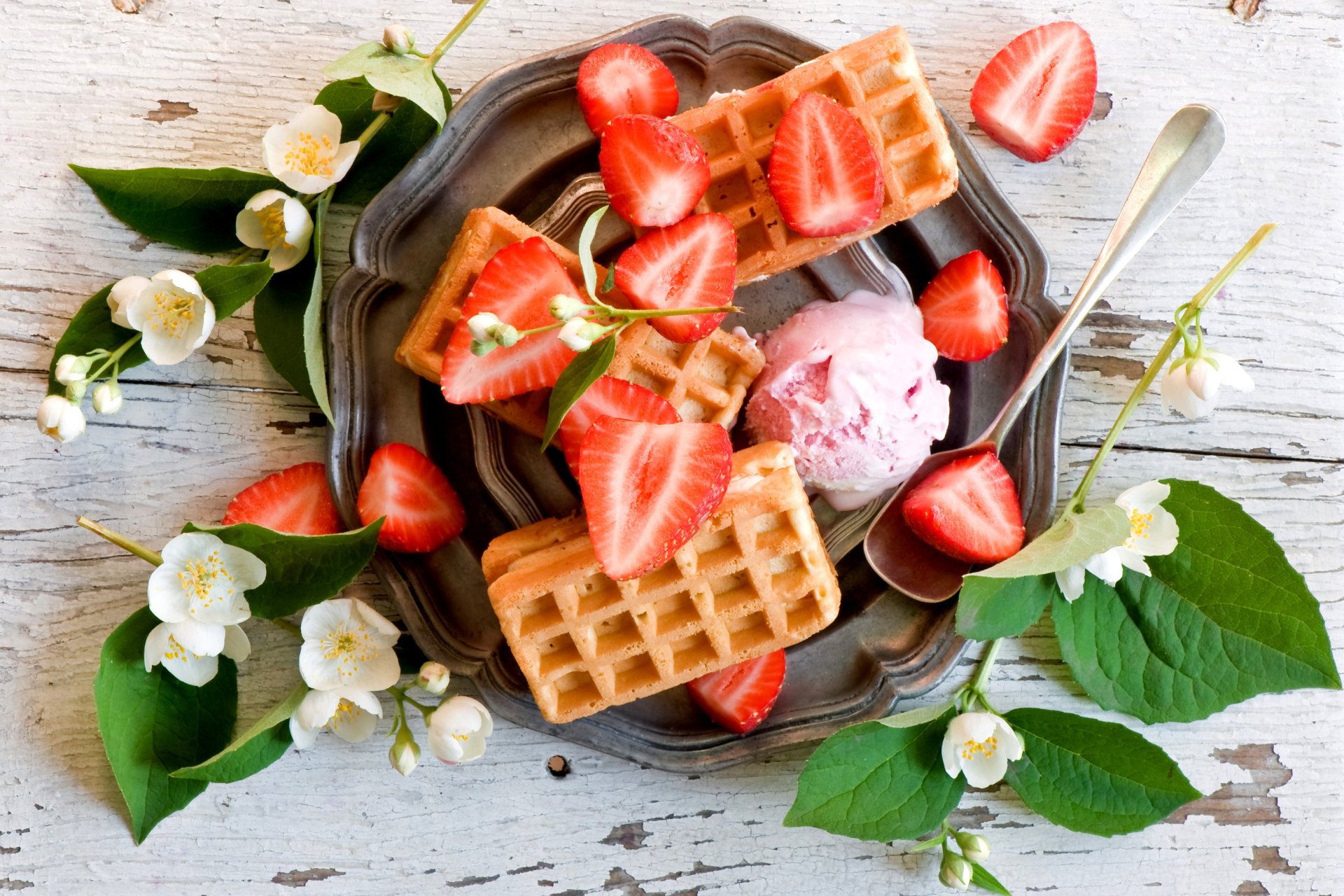 2K Quad HD PC desktop wallpaper: golden waffles with sliced strawberries and strawberry ice cream on a plate, accented by white blossoms on a rustic wooden background.
