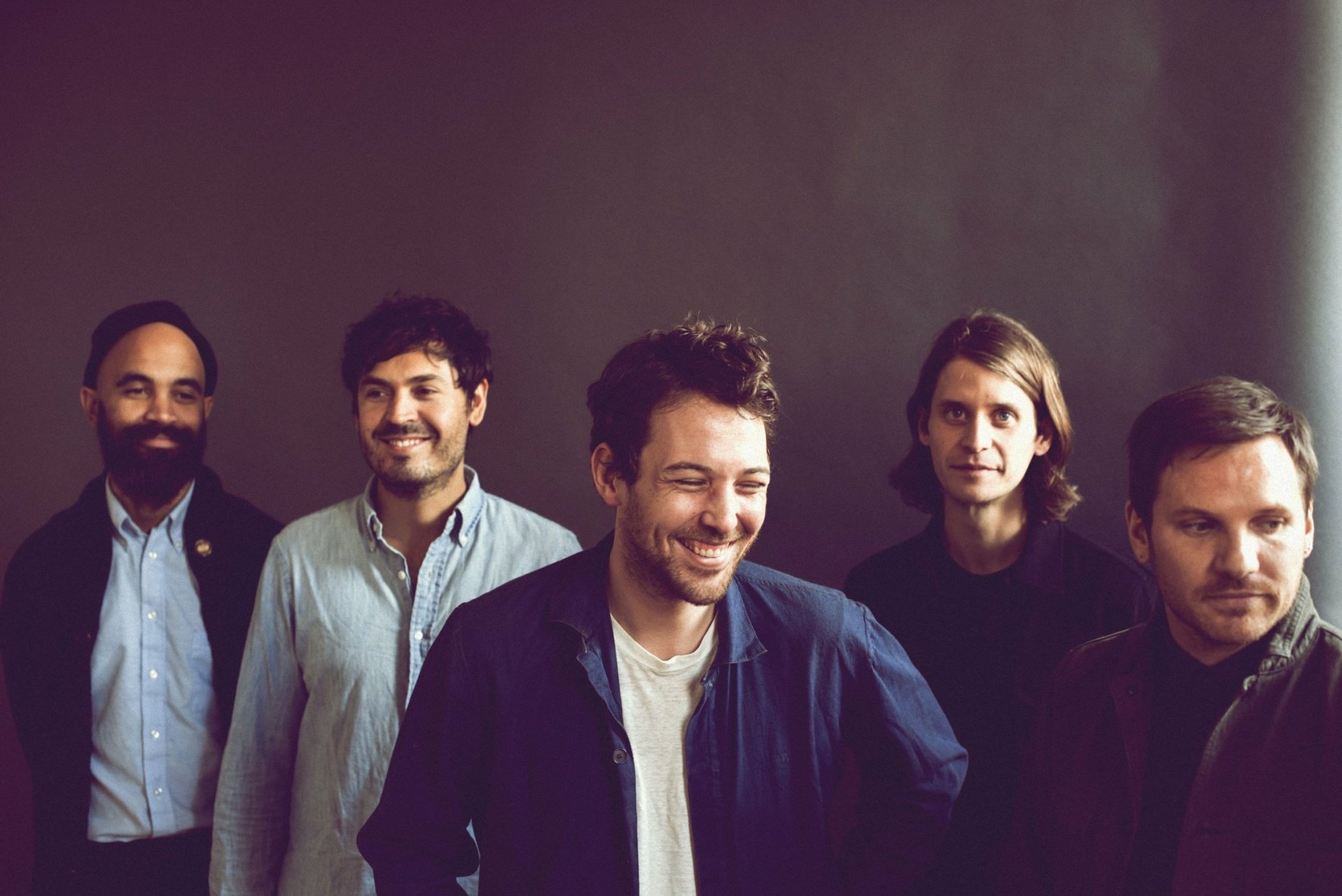 HD desktop wallpaper featuring the band Fleet Foxes, with members smiling in a group against a muted background.