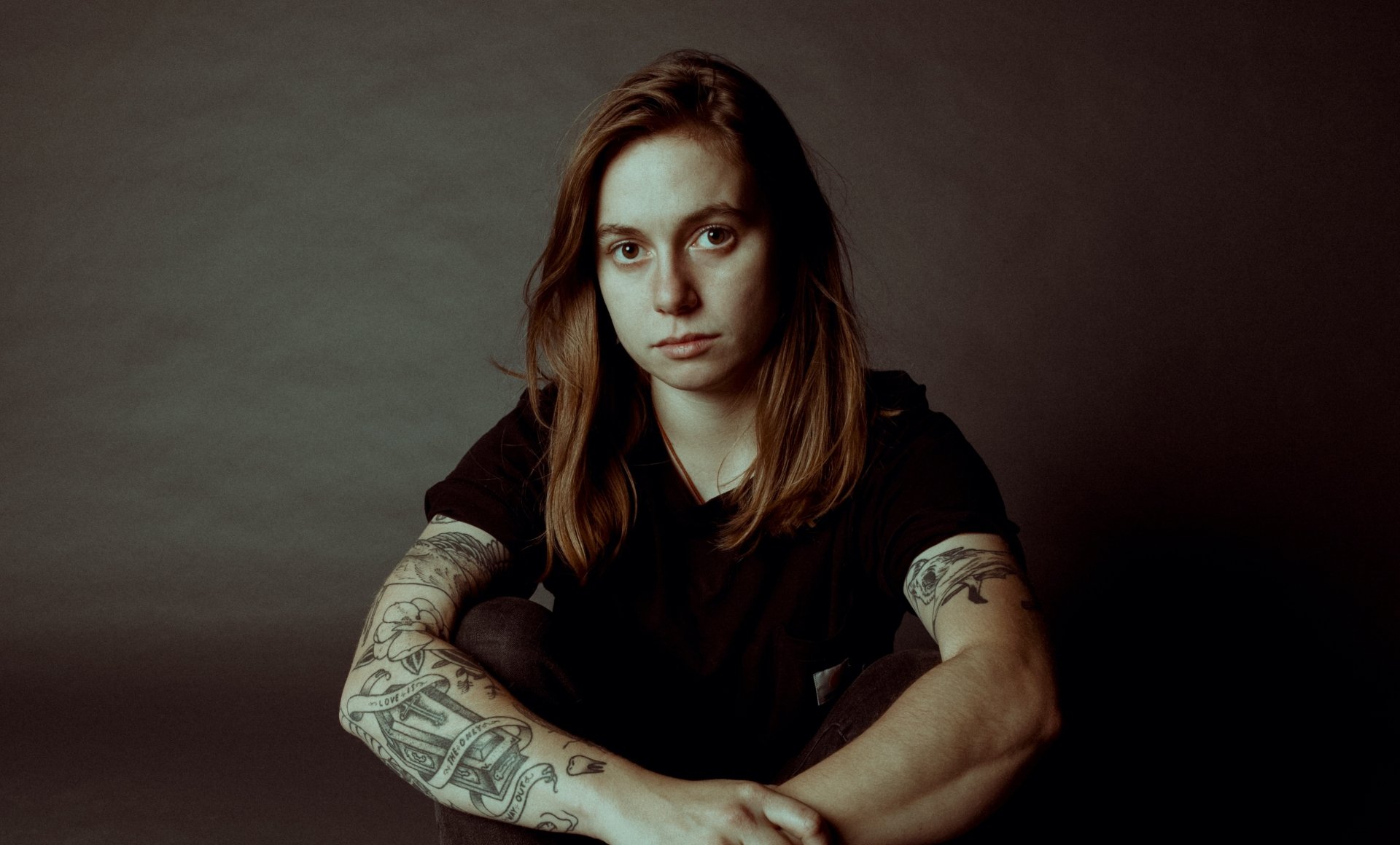 HD desktop wallpaper featuring a serious-looking individual with tattoos, suitable as a background, tagged Julien Baker.