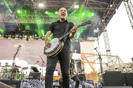 Energetic musician performing with a banjo on stage at a Dropkick Murphys concert, suitable as an HD desktop wallpaper and background.