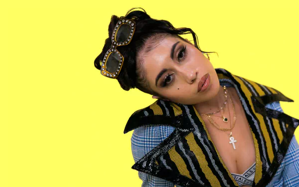 HD desktop wallpaper featuring an individual with a yellow background, stylish goggles on forehead, and a striking blue outfit.