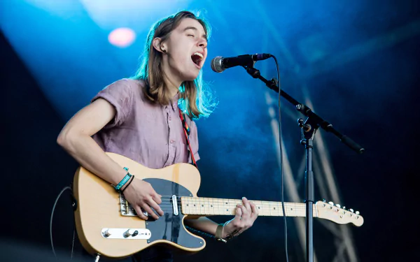 Julien Baker performing live with a guitar, in a vivid HD desktop wallpaper.