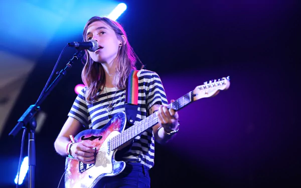 Musician with guitar singing into a microphone on stage, HD desktop wallpaper background.