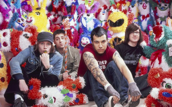 HD desktop wallpaper featuring a band with members seated against a colorful background of whimsical stuffed creatures, ideal for Fall Out Boy fans.