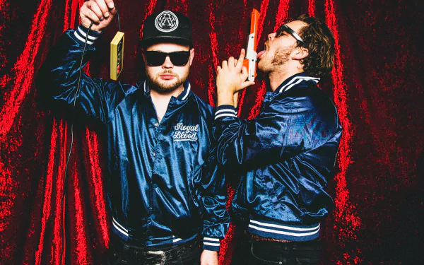HD desktop wallpaper featuring two members of Royal Blood in stylish jackets against a red velvet background, exuding a cool and edgy vibe.