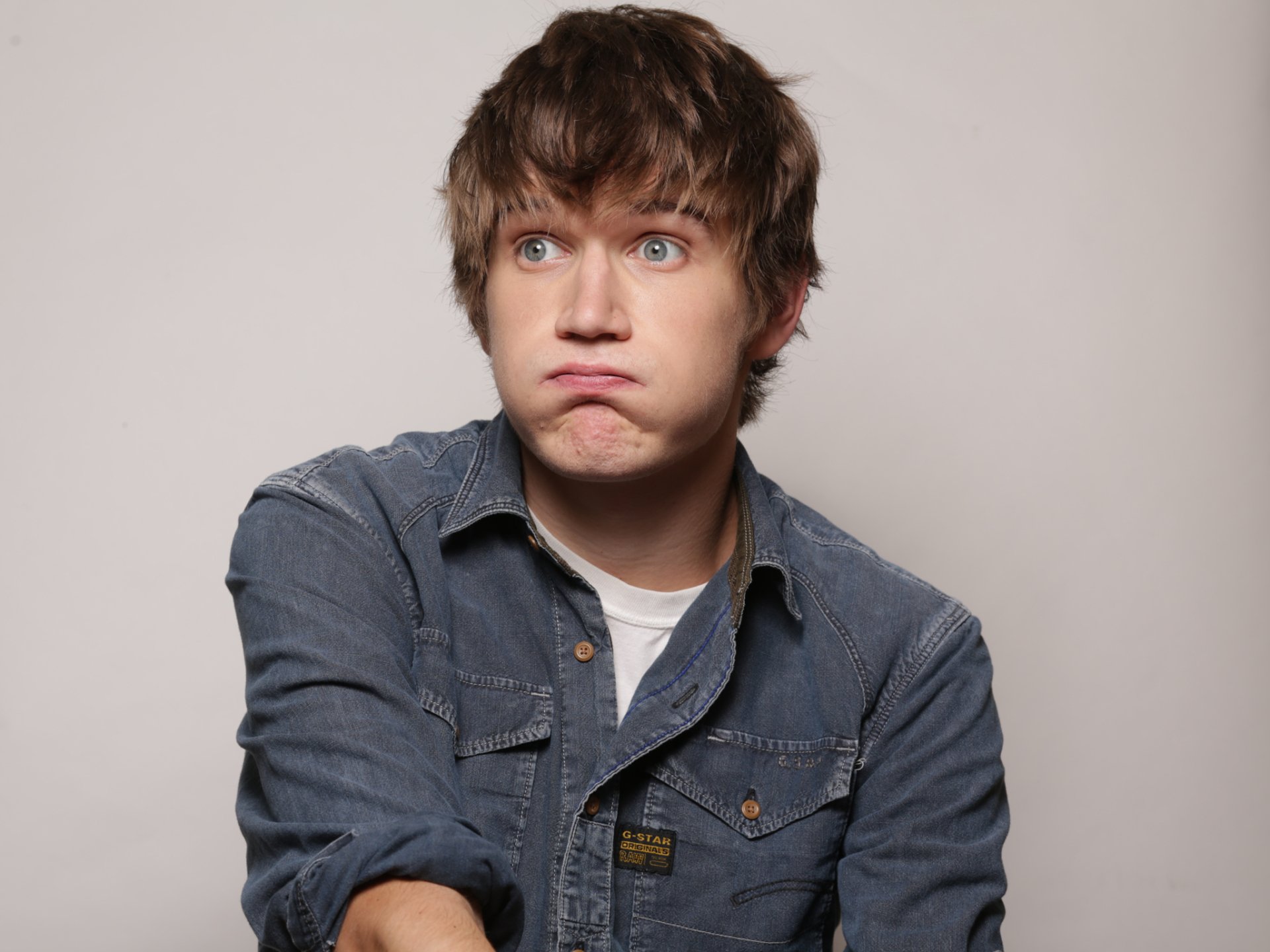 Quirky expression HD wallpaper featuring a young man in a denim shirt for desktop background.