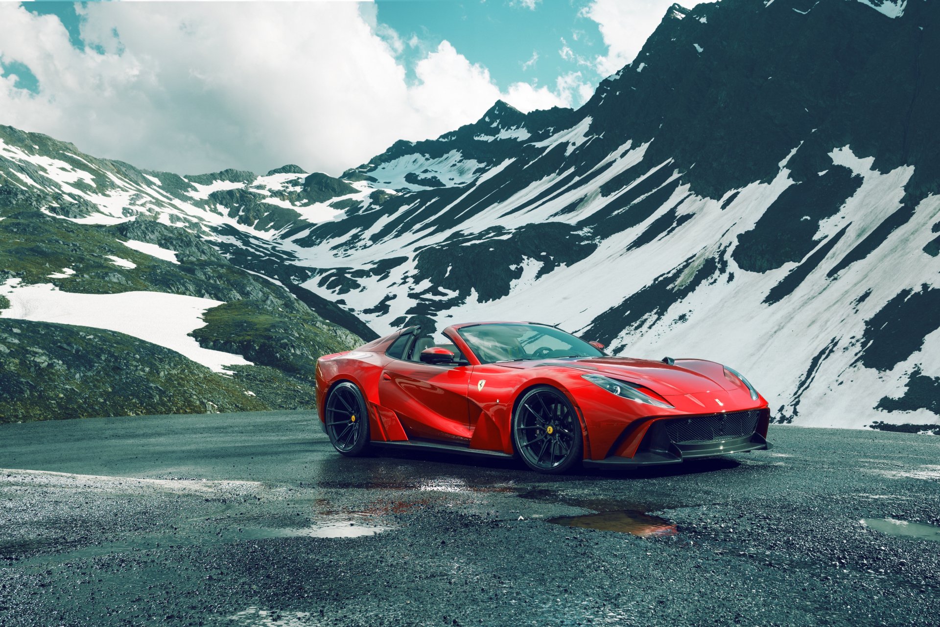 Red Ferrari 812 GTS supercar vehicle parked on a wet mountain road with snow-capped peaks — 5K Ultra HD PC desktop wallpaper/background.