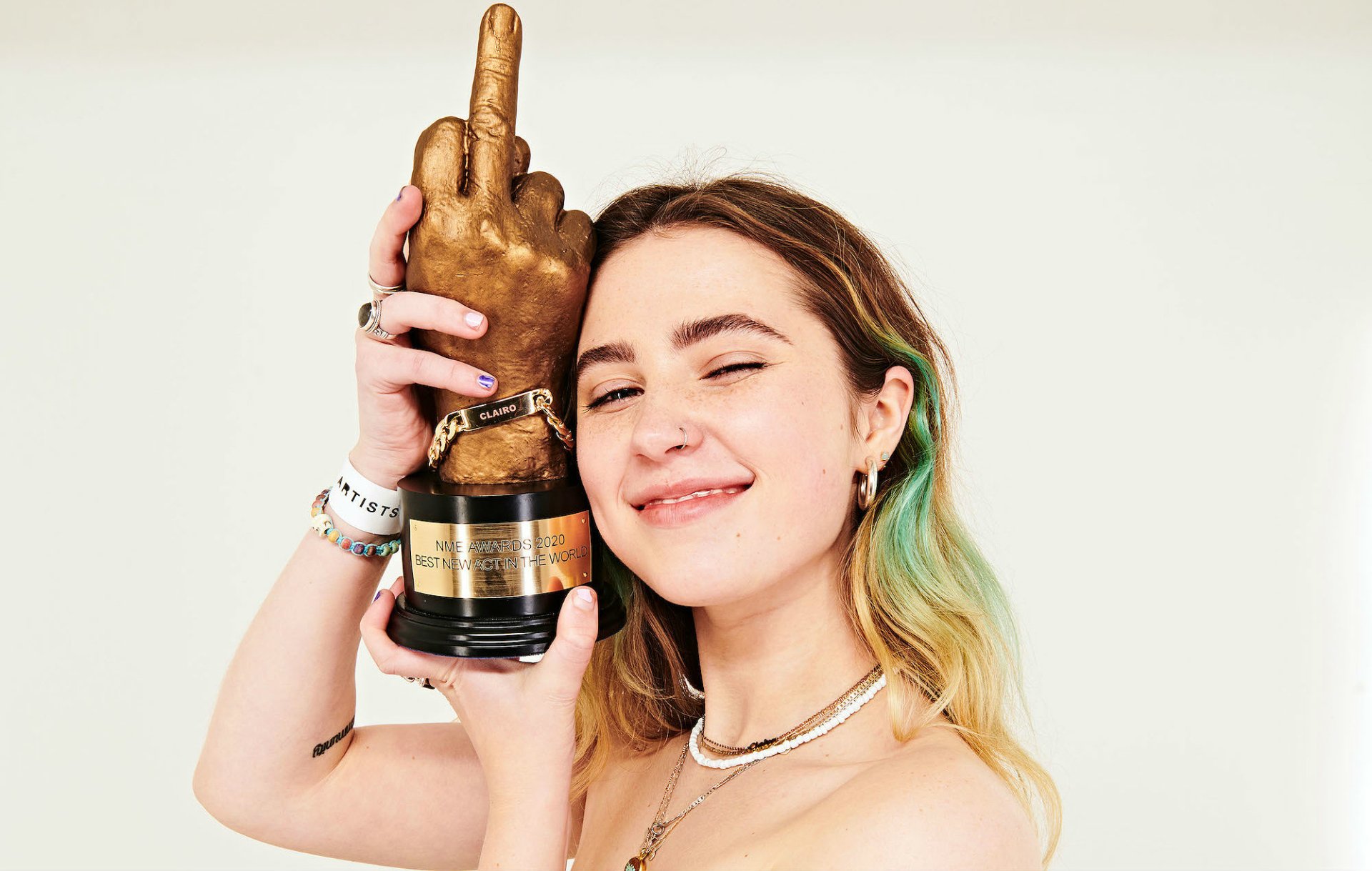 Smiling person holding an award trophy with a hand gesture, HD desktop wallpaper background tagged with Clairo.