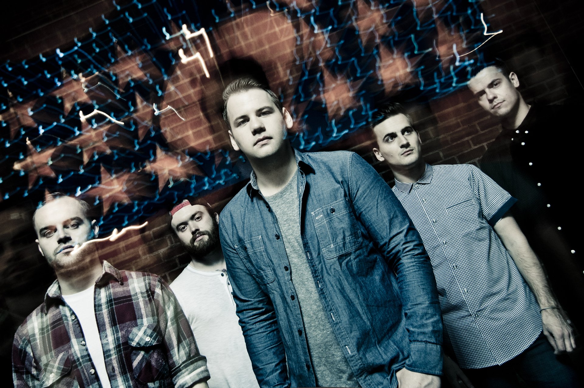 HD desktop wallpaper featuring a group of people with the tag Beartooth, posing against a brick wall with dynamic blue lighting effects.