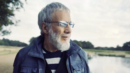 HD desktop wallpaper featuring a serene outdoor portrait of a bearded man with glasses, reminiscent of musician Cat Stevens, set against a tranquil natural background.