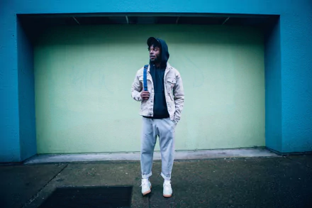 HD desktop wallpaper featuring Isaiah Rashad standing in front of a teal wall, exuding a cool, effortless vibe.