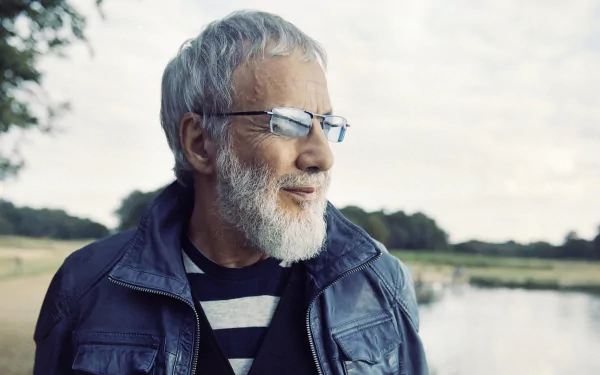 HD desktop wallpaper featuring a serene outdoor portrait of a bearded man with glasses, reminiscent of musician Cat Stevens, set against a tranquil natural background.