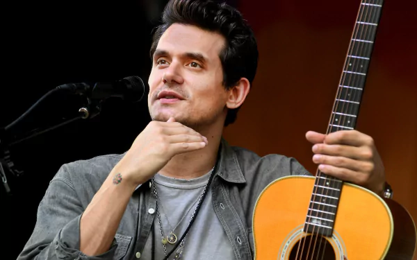 A close-up of John Mayer performing with his acoustic guitar, showcasing his expressive gesture and passion for music. This HD image serves as a vibrant desktop wallpaper.