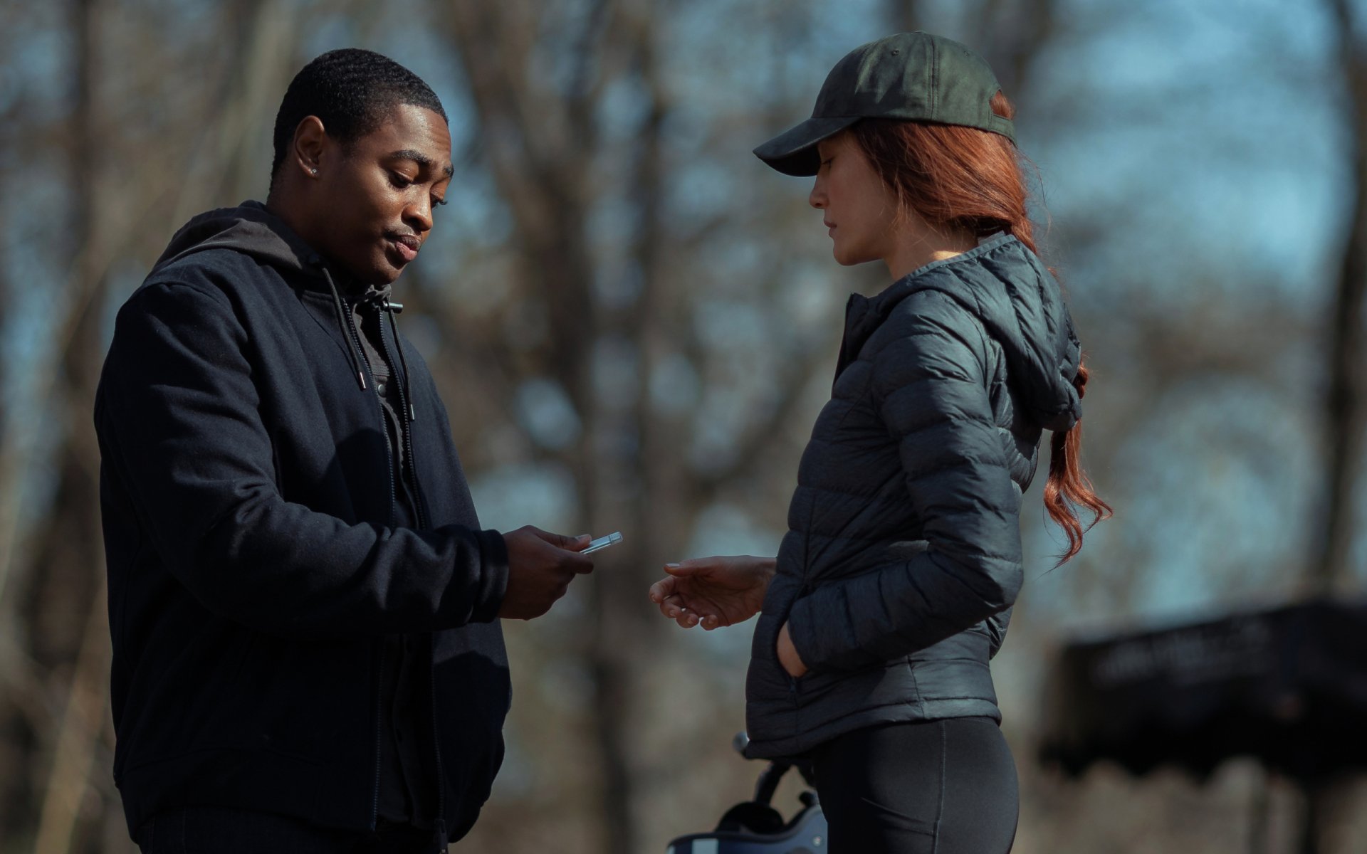 HD PC desktop wallpaper featuring Maggie Q in a scene from the movie The Protégé, showing two characters exchanging an item outdoors.