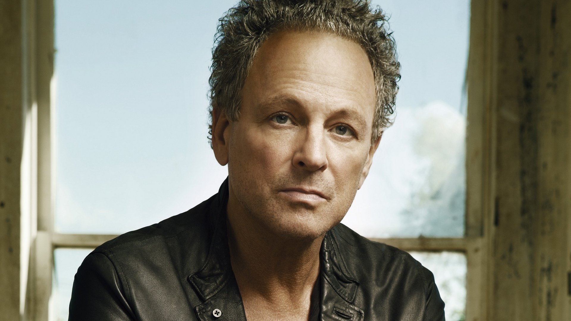 High-definition desktop wallpaper featuring a portrait of a man in a black leather jacket, with a thoughtful expression and a soft-focus background.