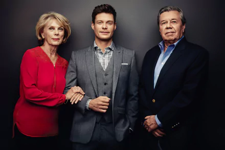 HD desktop wallpaper featuring three poised adults standing side by side against a dark background, with a woman in a red top to the left, a man in a checkered suit in the center, and a man in a dark blazer to the right.