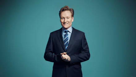HD wallpaper of a smiling man in a suit with a teal background.