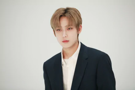 HD PC wallpaper: portrait of a young male K-pop singer in a dark blazer and white shirt against a minimal white background, music-themed desktop image.