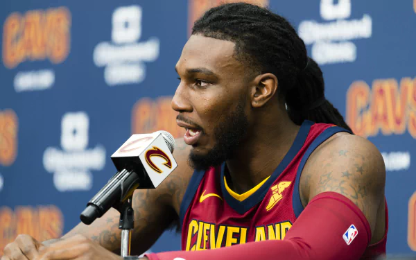 HD desktop wallpaper featuring a basketball player in a Cleveland Cavaliers jersey speaking into a microphone during a press event.