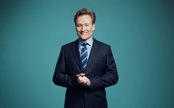 HD wallpaper of a smiling man in a suit with a teal background.