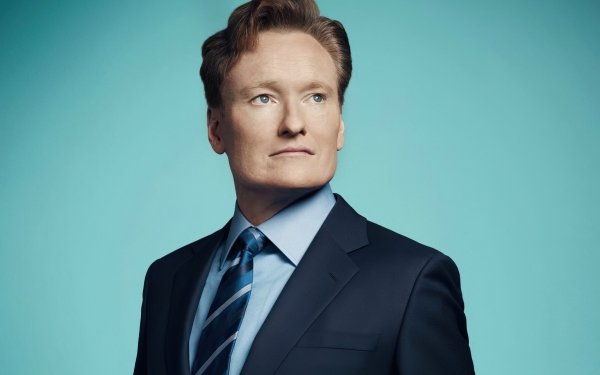 HD wallpaper featuring a man in a suit and tie against a teal blue background, perfect as a polished desktop background.