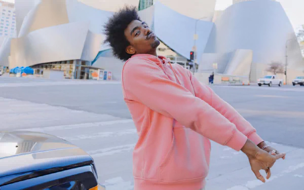 HD desktop wallpaper featuring a person in a pink hoodie stretching on an urban street with unique architecture in the background.