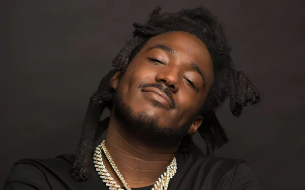 HD wallpaper featuring a person with closed eyes and a serene expression, adorned with necklaces, set against a dark background.