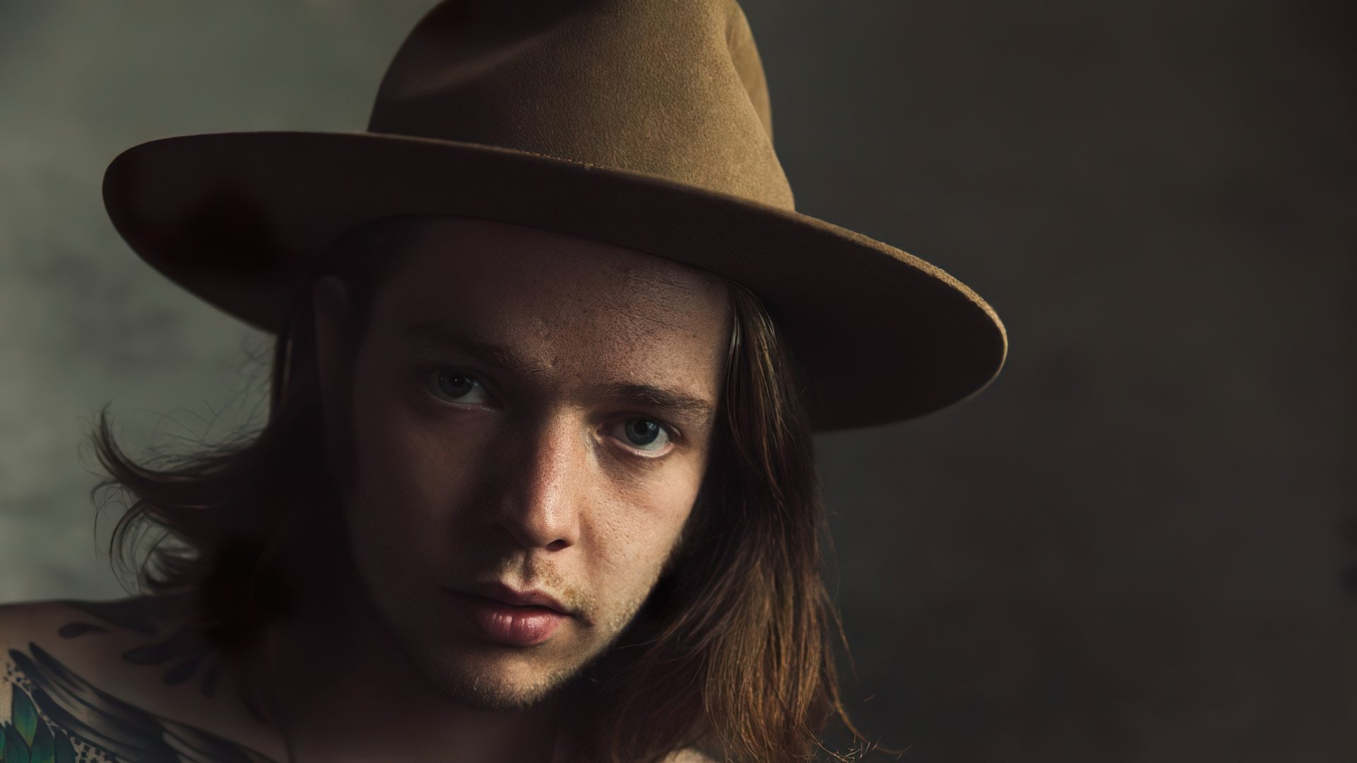 A close-up of Billy Strings, wearing a brown hat, gazing thoughtfully at the camera. This high-definition image serves as a captivating music-themed desktop wallpaper.