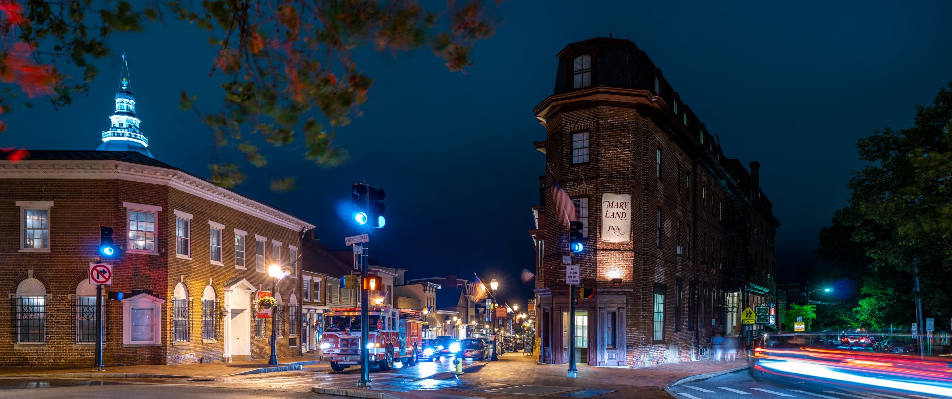 8K Ultra HD time-lapse image of a man-made city street at night, capturing vibrant light trails and historic urban buildings under a deep blue sky.