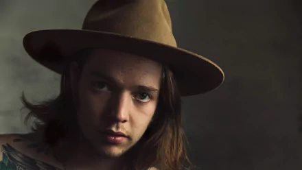 A close-up of Billy Strings, wearing a brown hat, gazing thoughtfully at the camera. This high-definition image serves as a captivating music-themed desktop wallpaper.