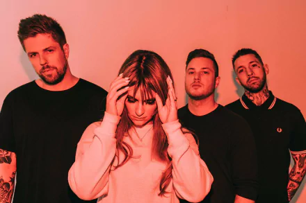HD wallpaper featuring a music group with a female member front and center, touching her temples, surrounded by three male members against a red background, tagged with Spiritbox.