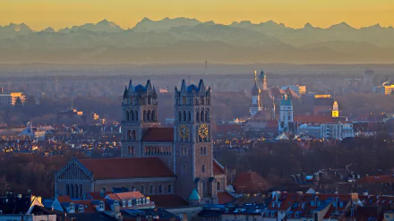 4K Ultra HD desktop wallpaper featuring a cityscape with prominent religious church towers against a backdrop of distant mountains at sunset.