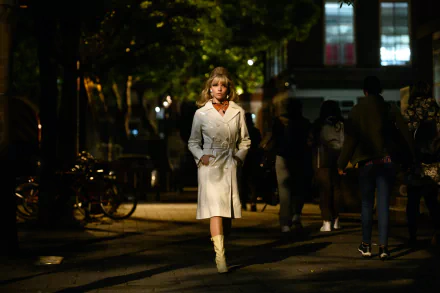 HD PC desktop wallpaper: an actress in a white coat walks a dim Soho street at night — cinematic movie still from Last Night in Soho.