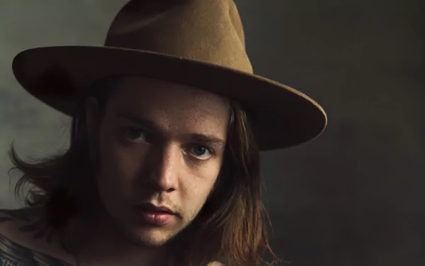 A close-up of Billy Strings, wearing a brown hat, gazing thoughtfully at the camera. This high-definition image serves as a captivating music-themed desktop wallpaper.