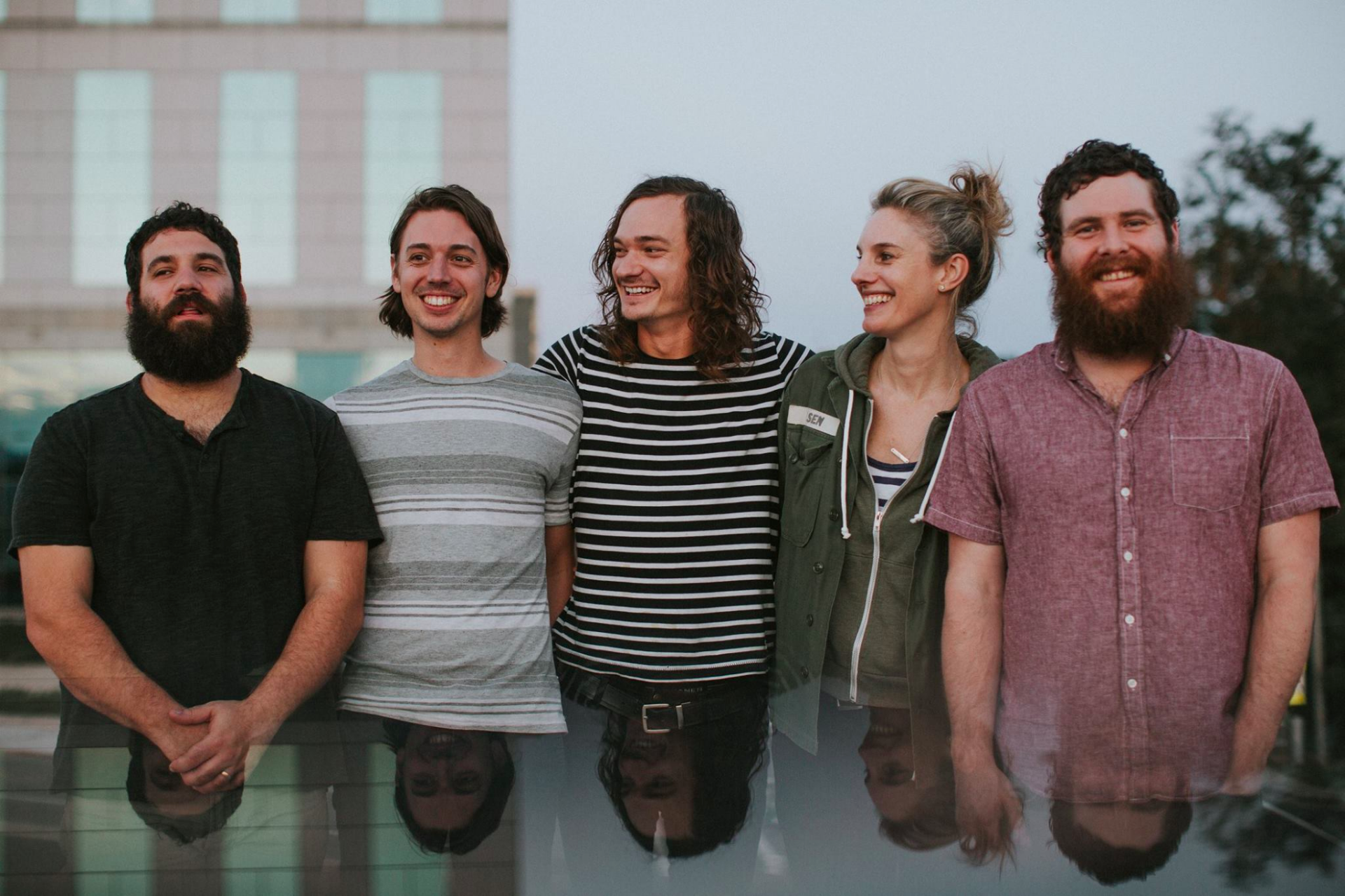 HD desktop wallpaper featuring the band Manchester Orchestra smiling together with a subtle cityscape backdrop.