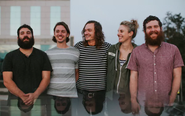 HD desktop wallpaper featuring the band Manchester Orchestra smiling together with a subtle cityscape backdrop.