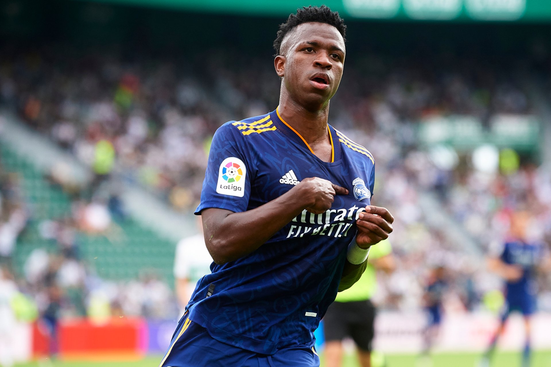 HD PC desktop wallpaper featuring Vinícius Júnior in action, wearing a blue Real Madrid sports jersey on the football field.