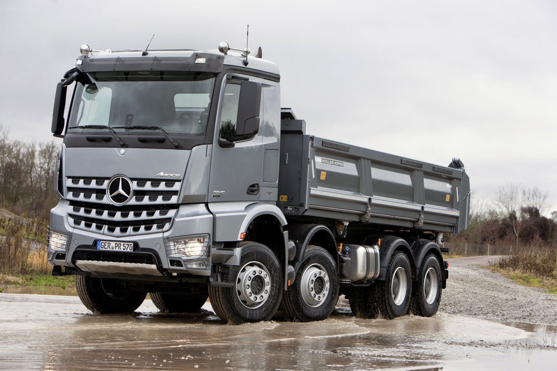 Silver Mercedes-Benz Arocs heavy-duty vehicle (dump truck) on a wet road — 2K Quad HD PC desktop wallpaper background.