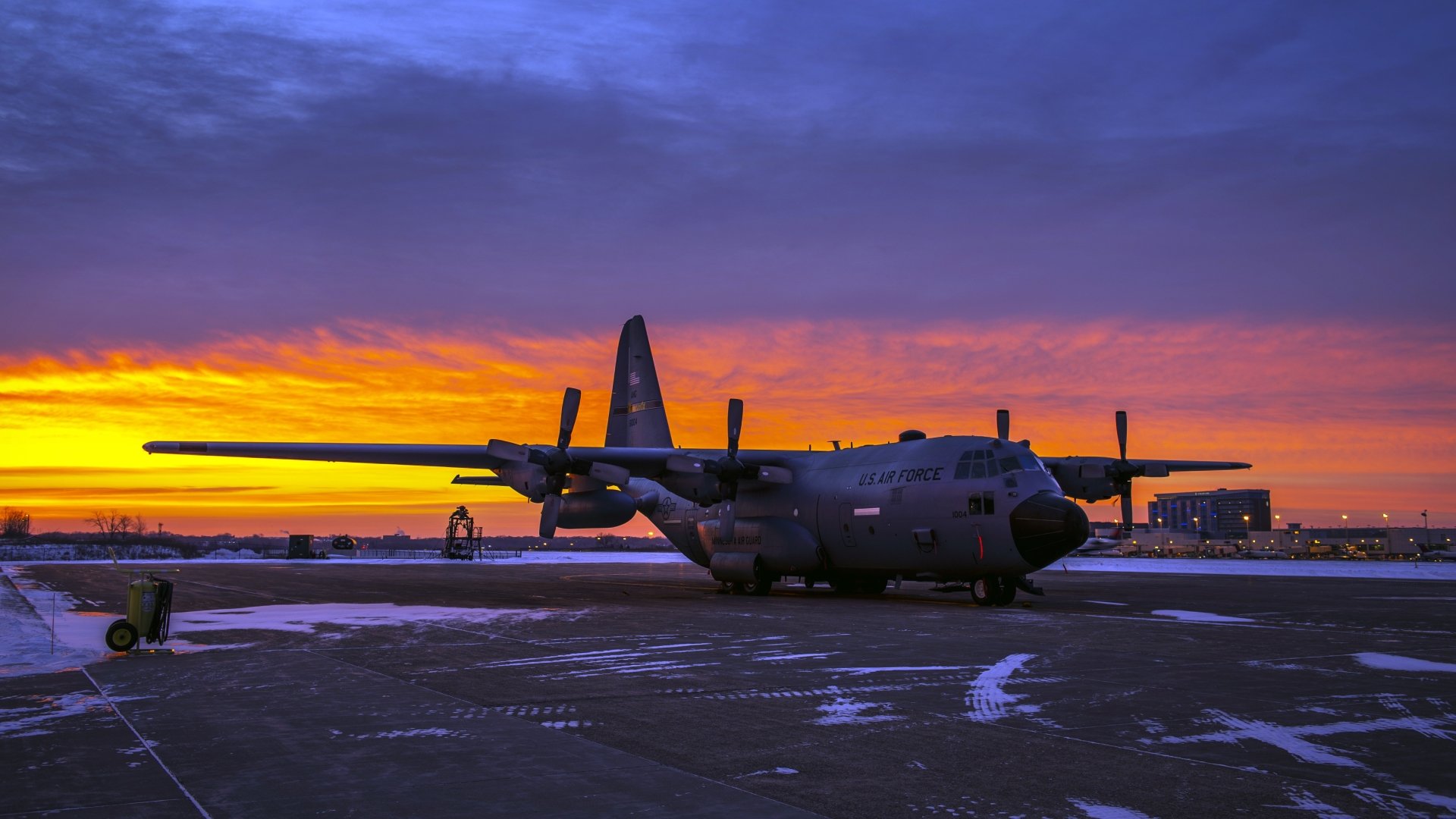 Lockheed C-130 Hercules military transport aircraft parked on a tarmac during a vibrant sunset, captured in 4K Ultra HD for a striking desktop wallpaper.
