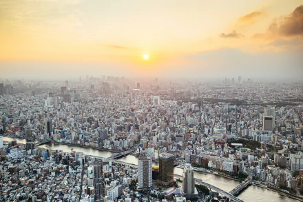 5K Ultra HD aerial view of Tokyo cityscape at sunrise, sprawling man-made skyline and river winding through a dense urban expanse — PC desktop wallpaper.