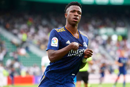 HD PC desktop wallpaper featuring Vinícius Júnior in action, wearing a blue Real Madrid sports jersey on the football field.