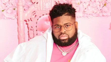 Stylish individual in a pink and white outfit with glasses posing against a pink floral backdrop for a trendy HD desktop wallpaper and background.