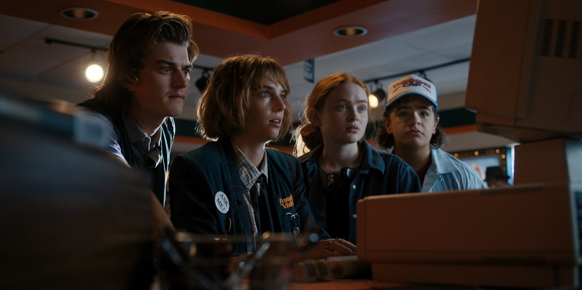 HD PC desktop wallpaper featuring a scene from the TV show Stranger Things, showing four main characters gathered around a computer.
