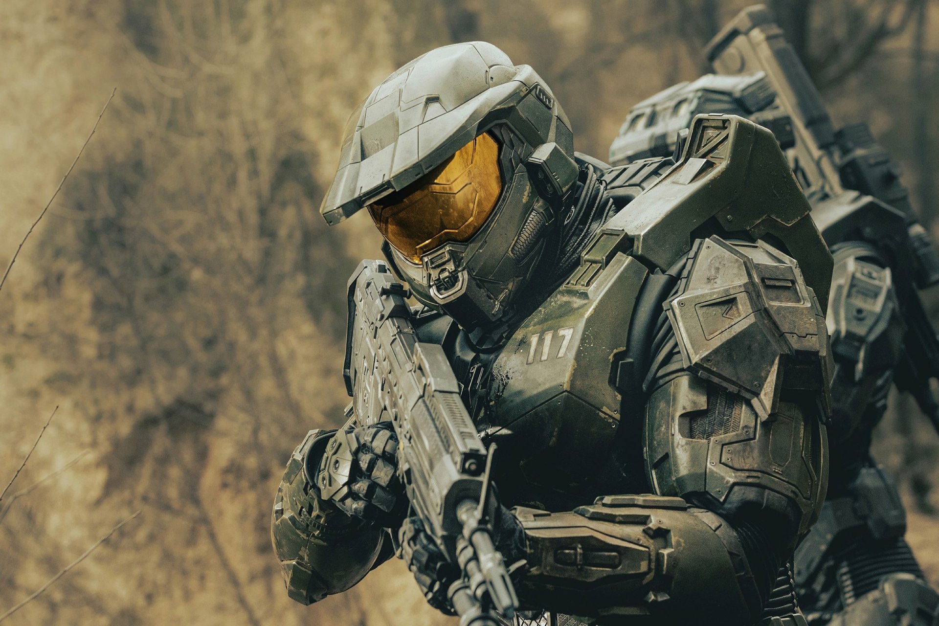 HD PC desktop wallpaper of Master Chief from the Halo TV show — armored Spartan in Mjolnir suit aiming a rifle against a rocky battlefield backdrop.
