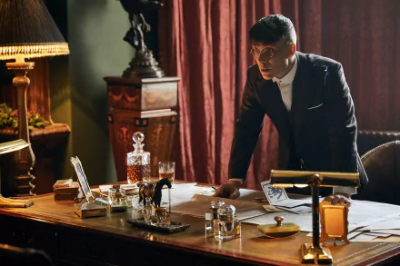 4K Ultra HD PC wallpaper: sharply dressed 1920s-style man leans over an ornate desk in a dim, smoky period office, vintage glassware and moody lighting creating a tense atmosphere.